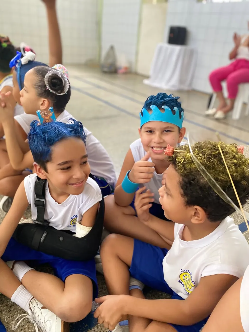 Alunos da Educação Infantil sorrindo, sentados juntos no pátio